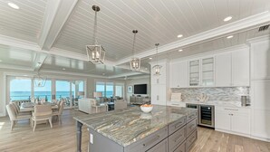 A spacious kitchen with a large island, white cabinetry, and a view of the ocean.