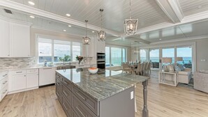 A spacious kitchen with a large island, white cabinetry, and pendant lighting.
