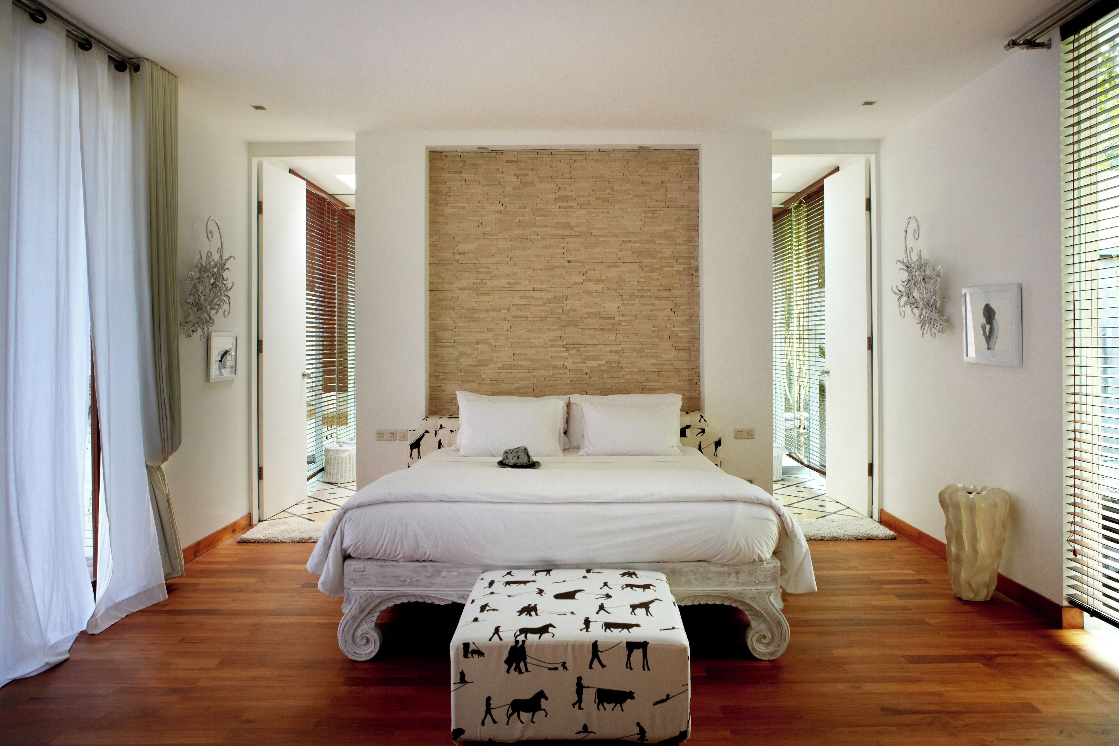 Un dormitorio con una cama grande, suelo de madera y pared de ladrillo decorativa.