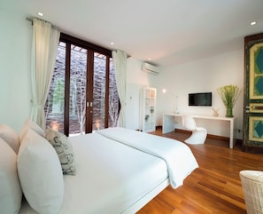 A modern bedroom with a large bed, a desk, and a television. - Pure Villa Bali by Nagisa Bali (Canggu)