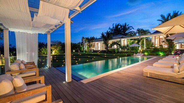 Un espace aménagé au bord de la piscine, avec une terrasse en bois, des chaises longues et des parasols.