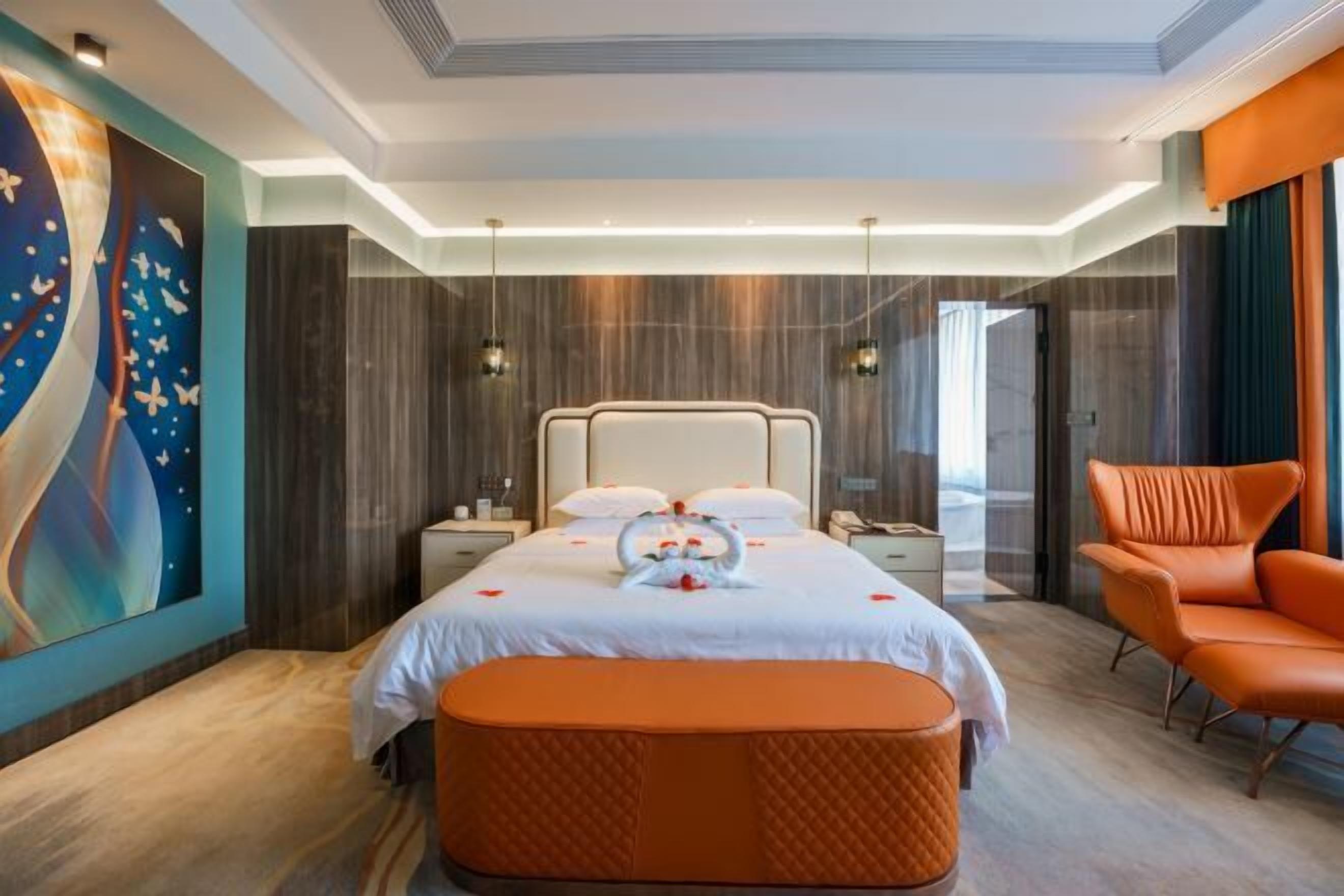 A modern hotel room with a large bed, a bench, a chair, and a large abstract painting on the wall.
