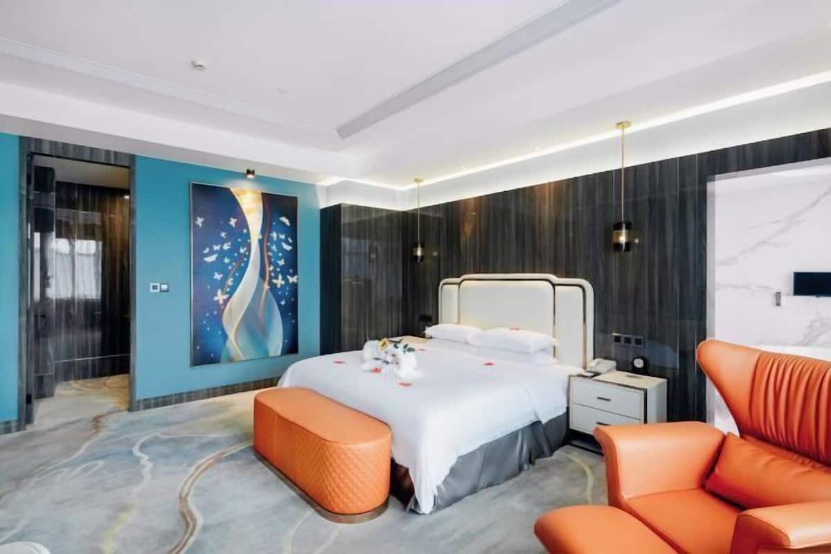 Una habitación de hotel moderna con una cama grande, un área de descanso y un cuadro en la pared.