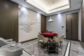 A dining area with a table covered by a red cloth, surrounded by chairs, and a wall mural.