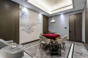 Un comedor con una mesa cubierta por un mantel rojo, rodeado de sillas y un mural en la pared.