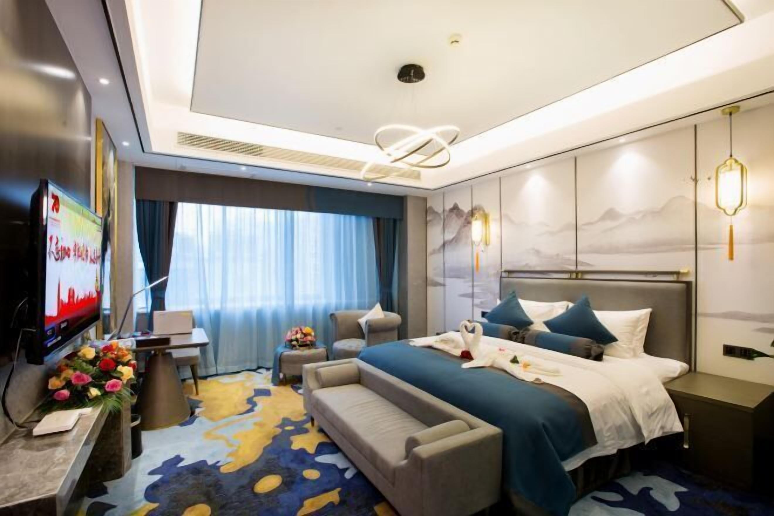 A modern hotel room with a large bed, a TV, a desk, and a sofa.