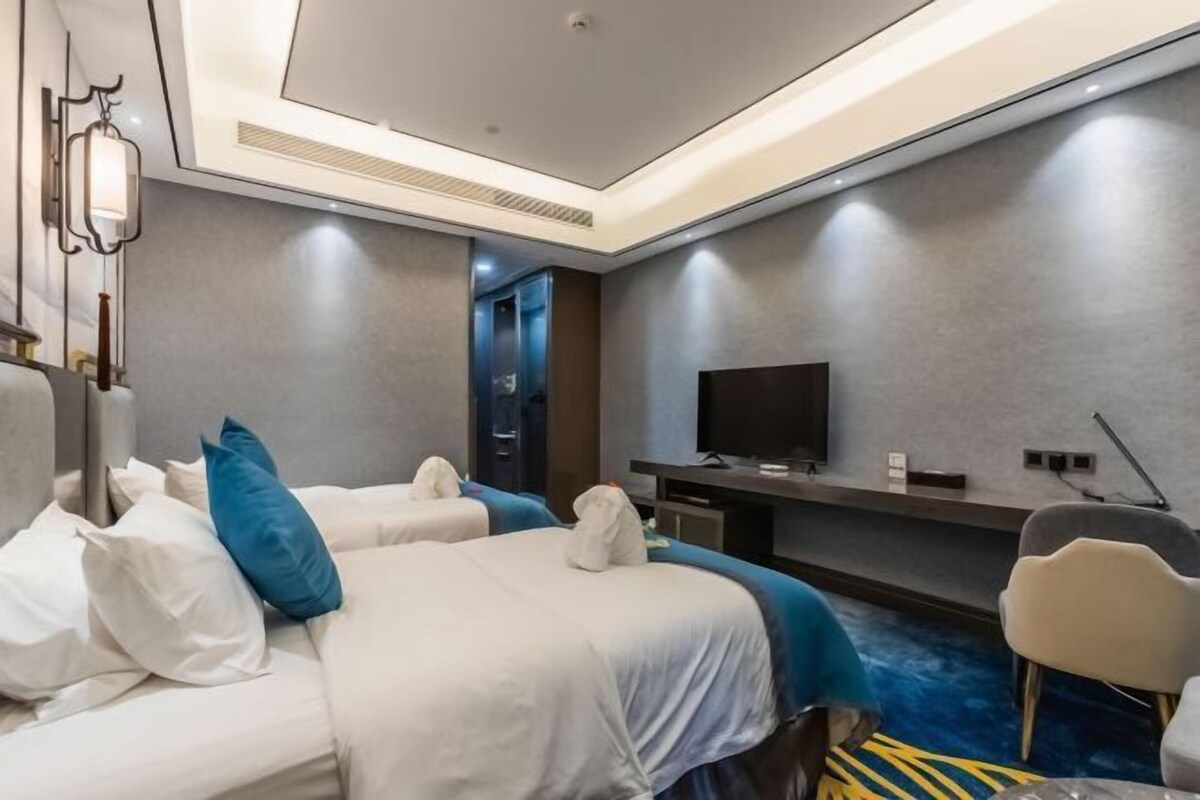 A hotel room with two beds, a flat-screen TV, a desk, and a chair.