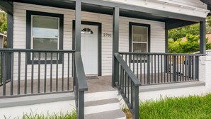 Une maison blanche avec un porche, des balustrades noires et une porte portant le numéro « 2701 ».