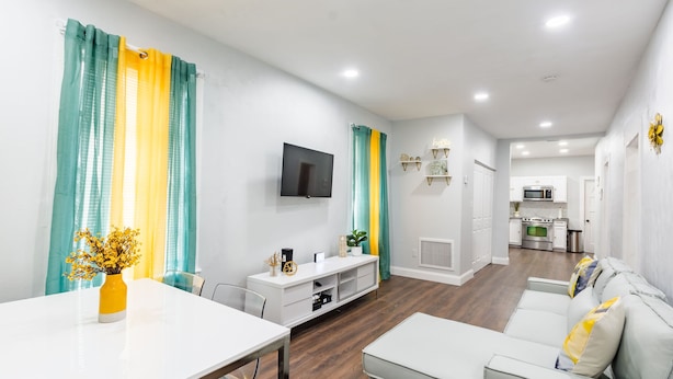Un salon moderne comprenant un canapé, un téléviseur et un coin repas avec une table et des chaises.