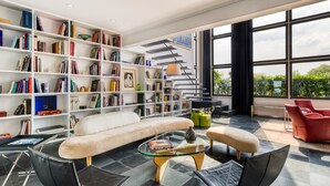 Ein modernes Wohnzimmer mit einem weißen Sofa, einem Glastisch und einem Bücherregal voller Bücher.