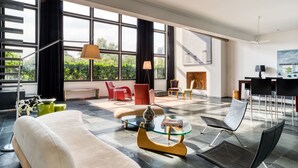 Ein geräumiges Wohnzimmer mit großen Fenstern, modernen Möbeln und einem Kamin.