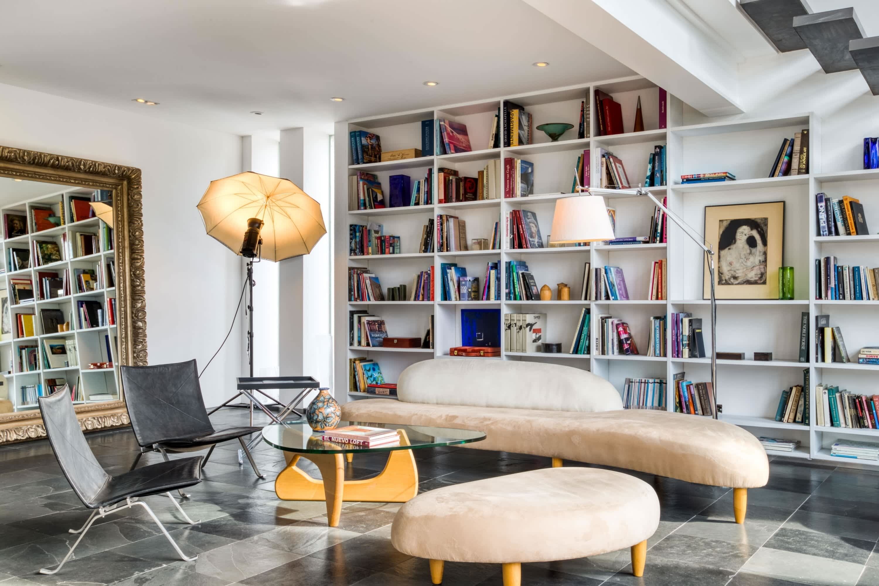 A modern living room with a large bookshelf, a glass coffee table, and a comfortable sofa.