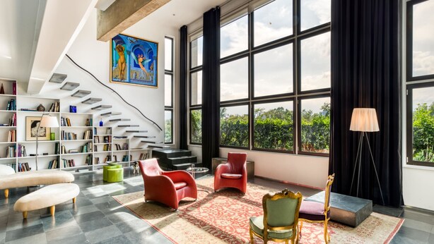 Ein geräumiges Wohnzimmer mit großem Fenster, einer Treppe und einem Bücherregal voller Bücher.