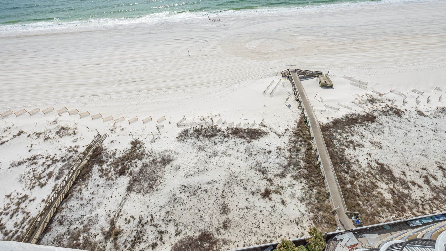 Une plage avec une promenade en bois menant à une structure également en bois, qui pourrait être un abri de plage ou un poste de surveillance des sauveteurs.