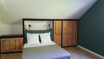 Une chambre à coucher avec un lit, une armoire en bois et un bureau avec une lampe.
