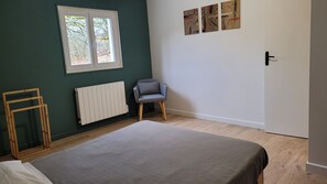 Une pièce avec un lit, un radiateur, une chaise et une fenêtre donnant sur des arbres.