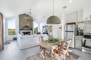 Una cocina moderna con comedor, muebles blancos y chimenea.