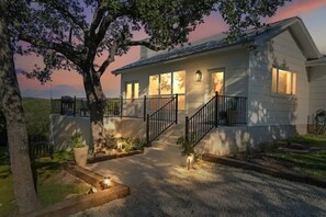 Ein zweistöckiges Haus mit Veranda, Treppe und Auffahrt.