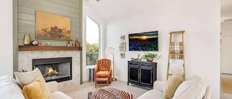 A living room with a fireplace, a sofa set, a chandelier, and a television.