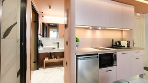 Une cuisine moderne dotée d’appareils électroménagers en acier inoxydable, d’un four encastré et d’un four à micro-ondes. On y trouve un banc en bois sous le plan de travail et un petit coin évier.