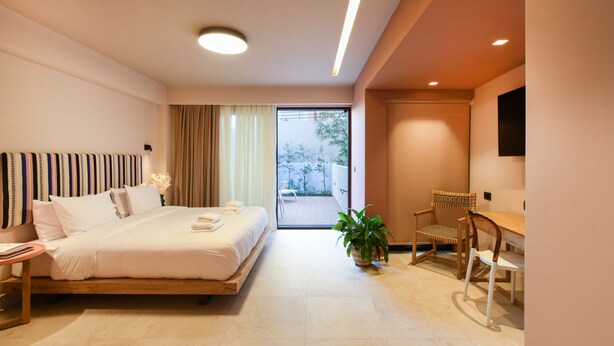 Une chambre d’hôtel moderne avec un grand lit, un bureau et une chaise. Il y a une fenêtre avec des rideaux et une vue sur l’extérieur.