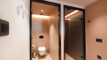 Un baño moderno con inodoro, bidé y cabina de ducha de vidrio.