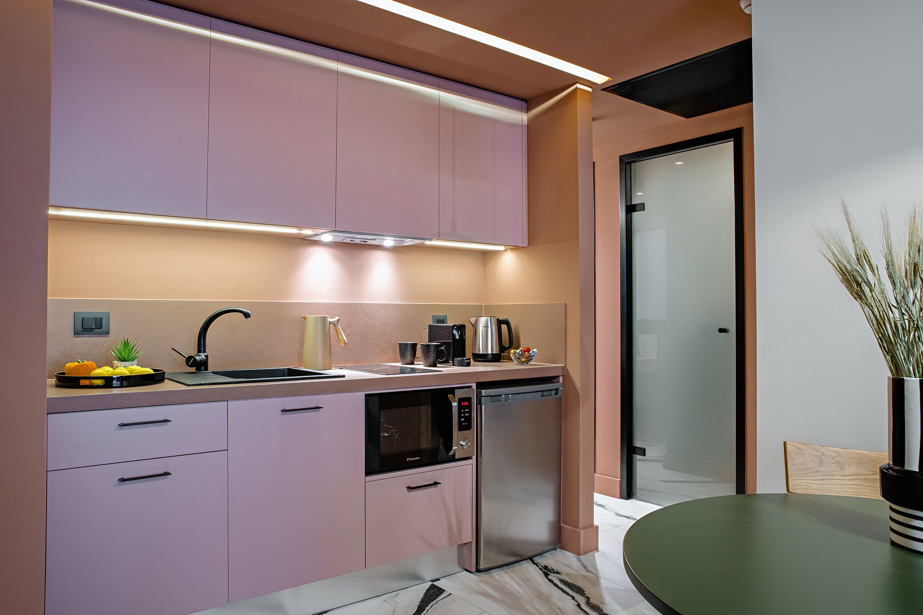 Une cuisine moderne équipée d’un four à micro-ondes encastré, d’un lave-vaisselle et d’un petit coin repas avec une table et des chaises.