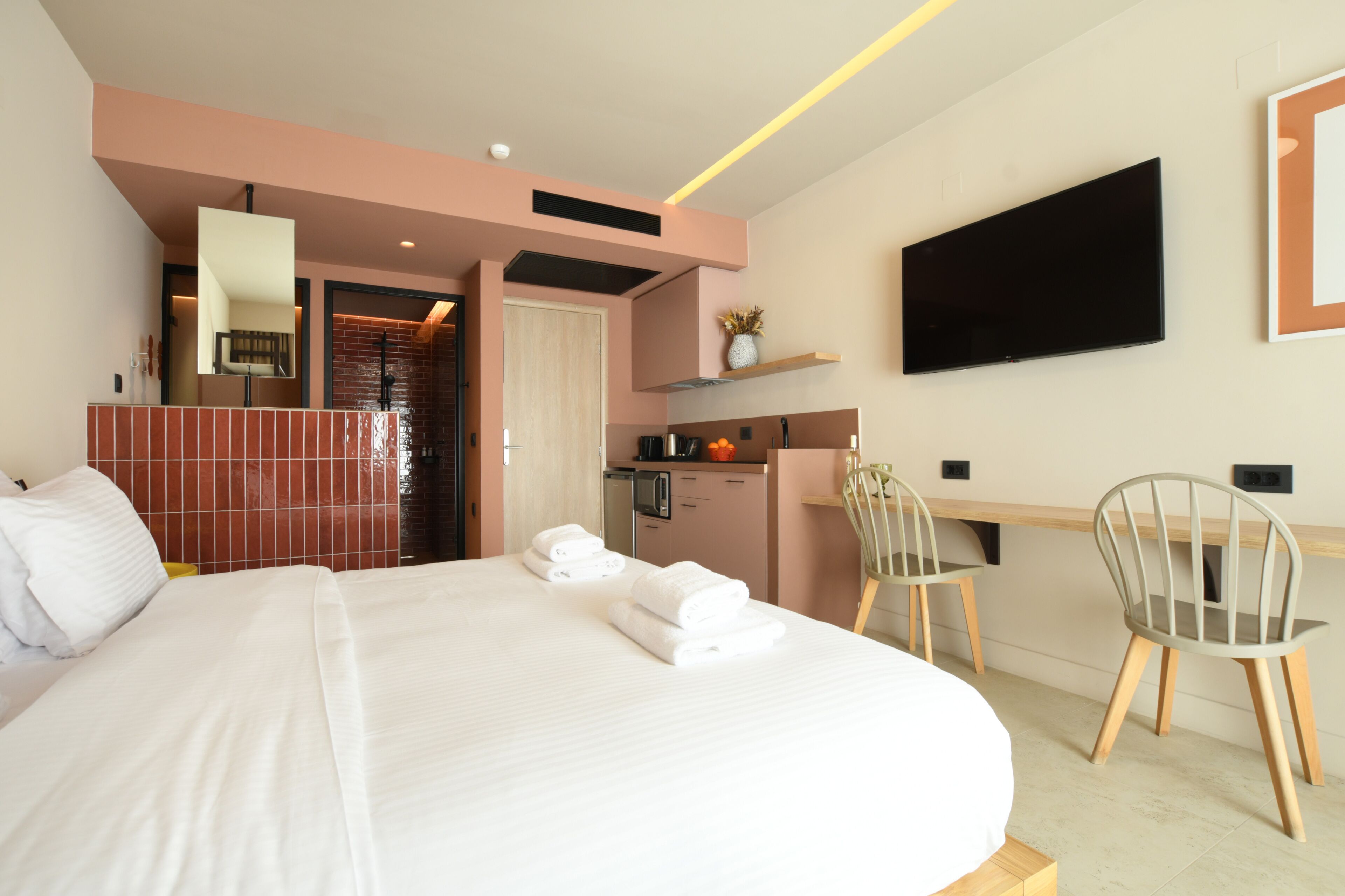 Een hotelkamer met een groot bed, een bureau met stoel, een televisie en een kitchenette.