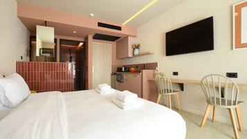 Een hotelkamer met een groot bed, een bureau met stoel, een televisie en een kitchenette.