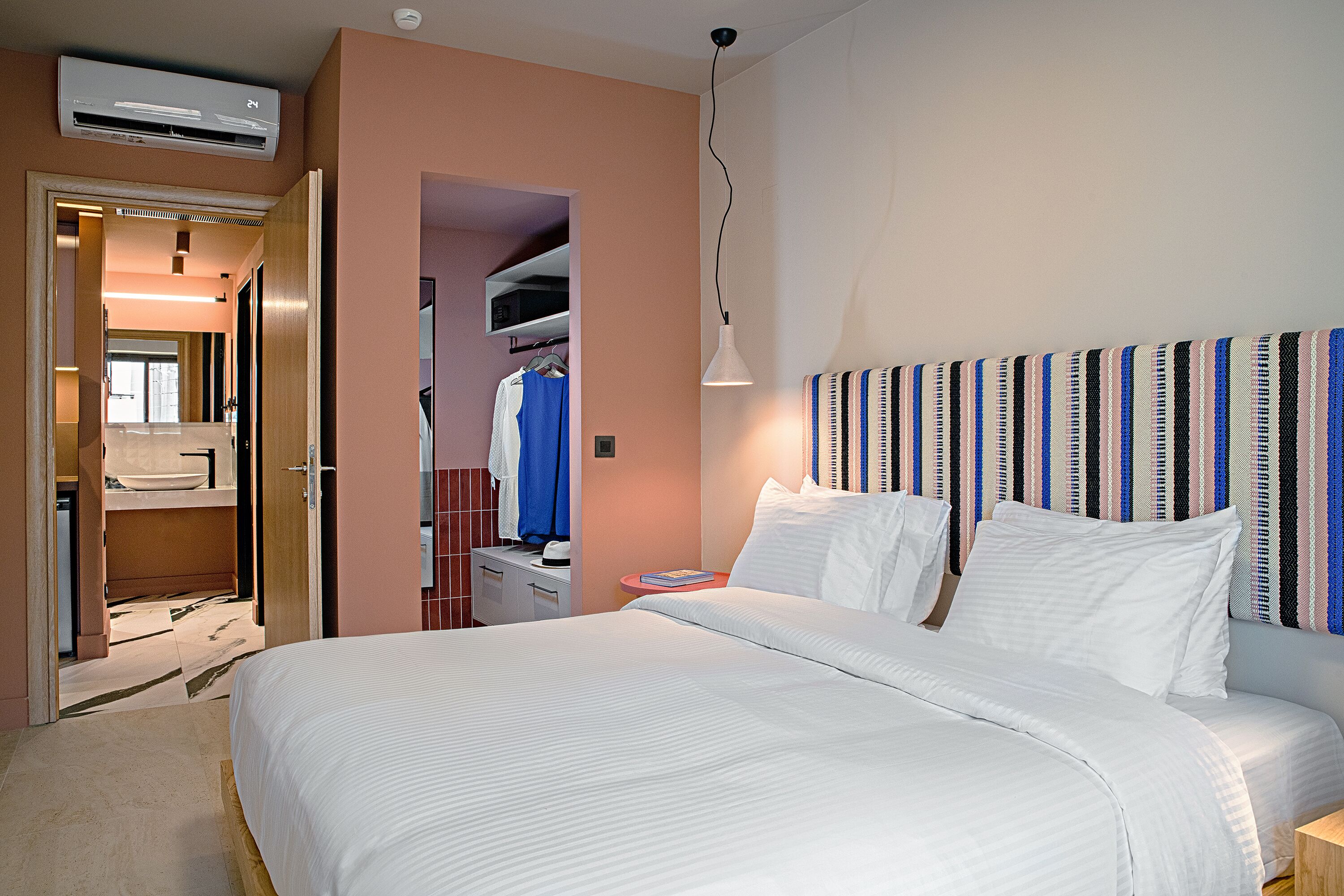 Une chambre d’hôtel avec un grand lit, une armoire, une table de chevet et un appareil de climatisation.