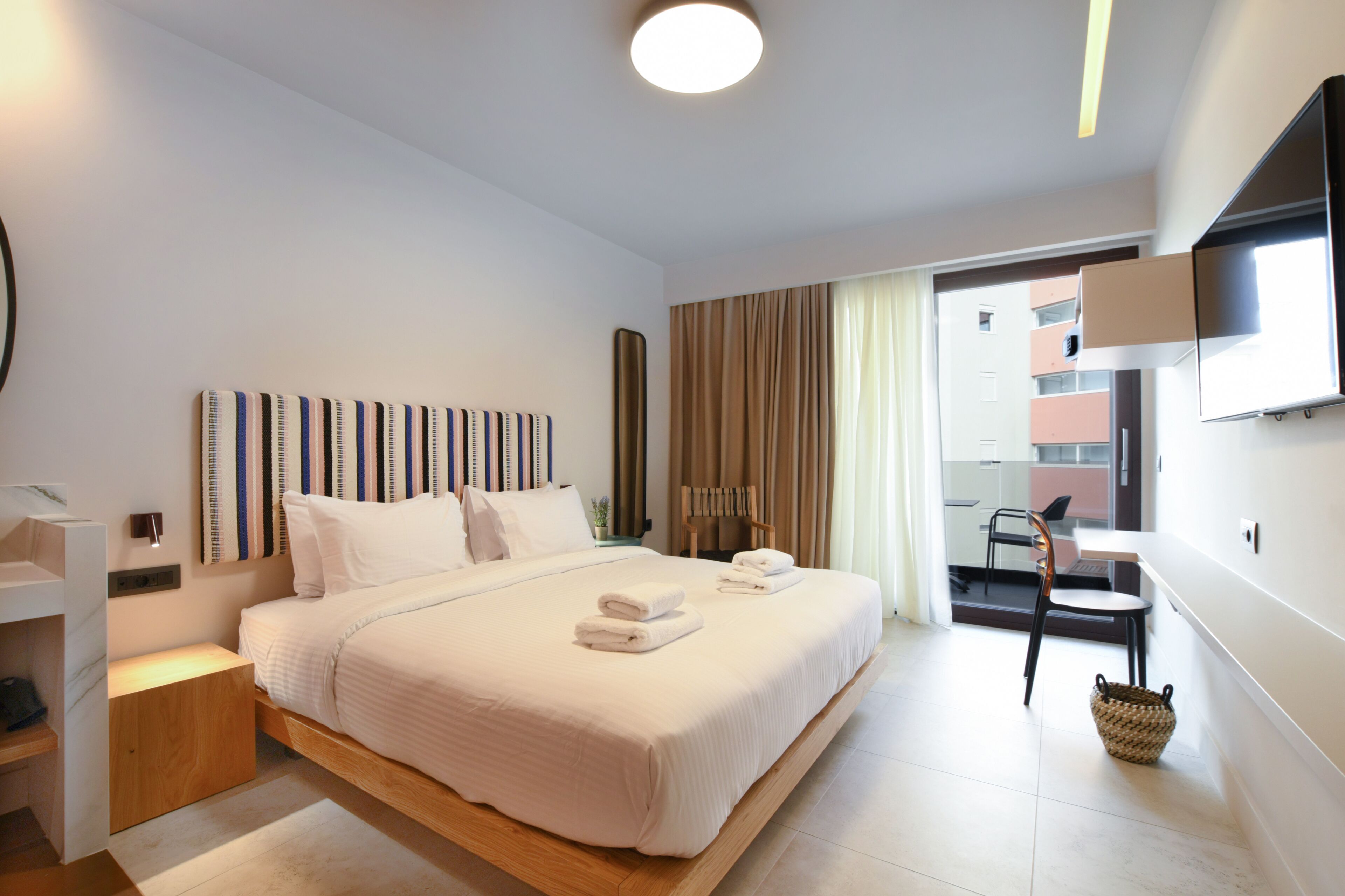 Una habitación de hotel moderna con una cama grande, un escritorio y una televisión.