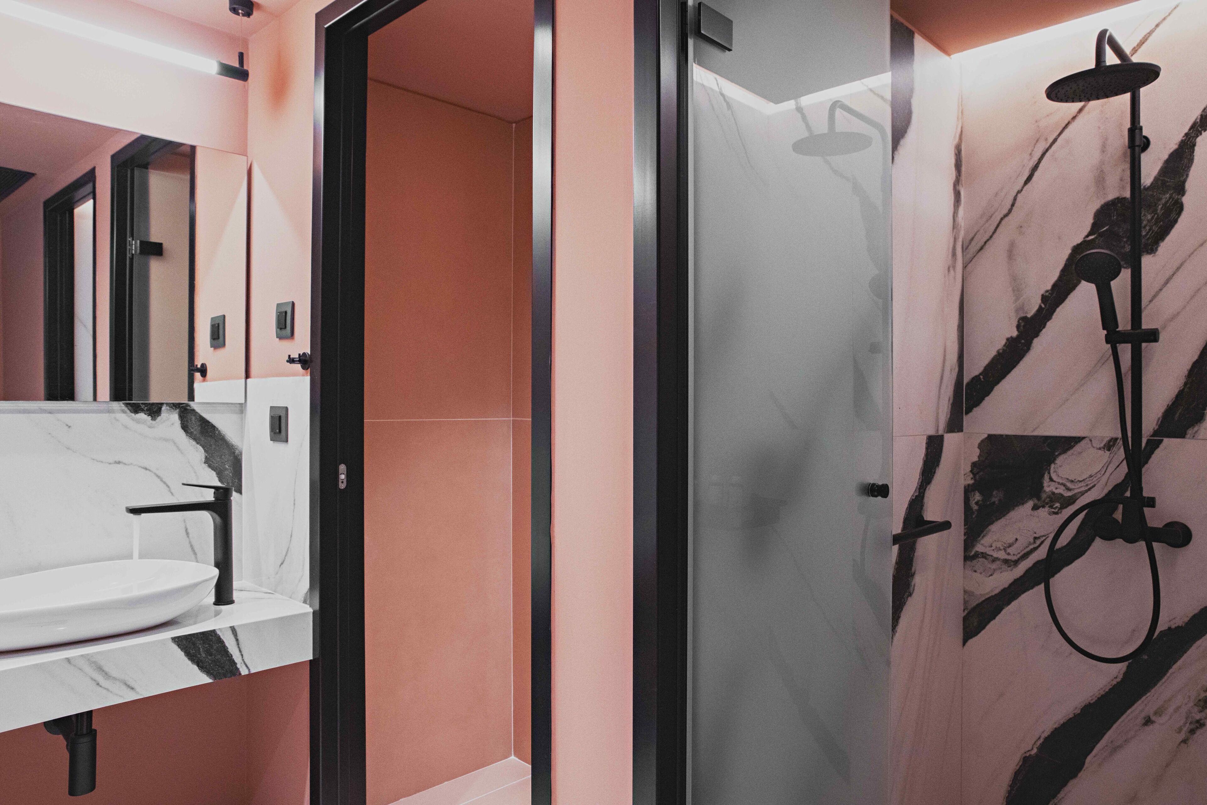 Une salle de bain moderne avec un lavabo en marbre, une cabine de douche en verre et un motif mural en marbre.
