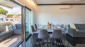 Ett modernt matområde med ett glasbord, grå stolar och en soffa.