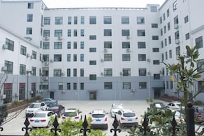 A multi-story building with a parking lot in front. - Xingshan Luoma Holiday Hotel (Xingshan)