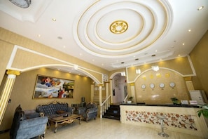 A hotel lobby with a reception desk, seating area, and a staircase.