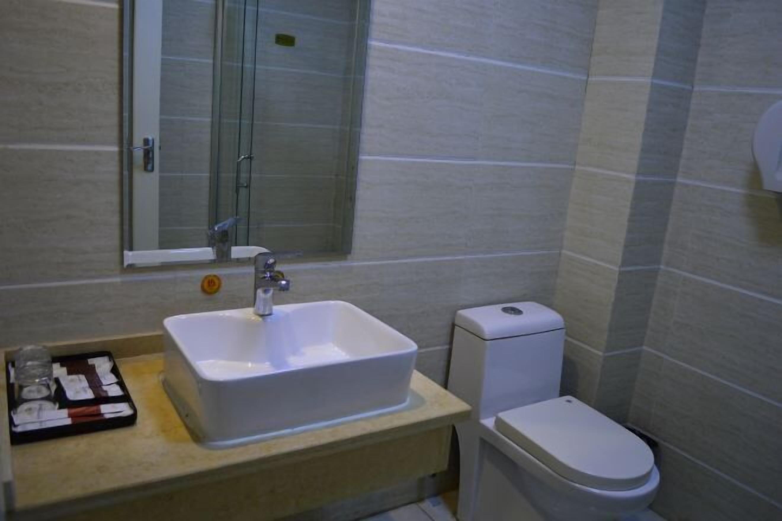 Ein Badezimmer mit einem weißen Waschbecken, einer Toilette und einer Duschkabine aus Glas.