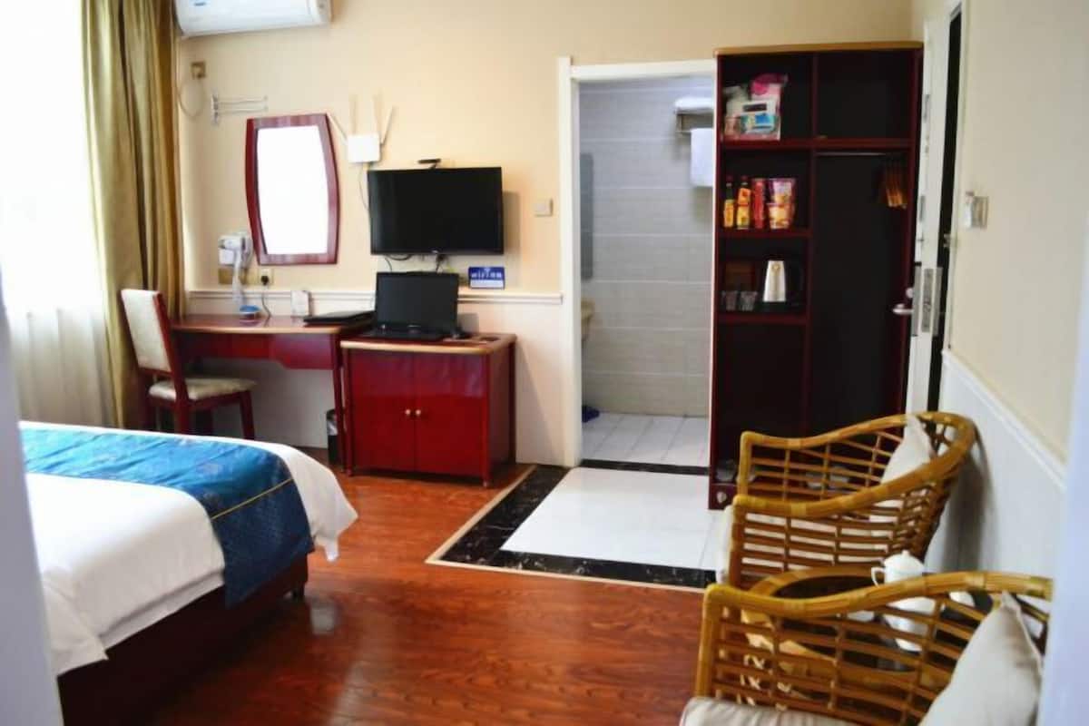 Une chambre d’hôtel comprenant un lit, un bureau, une chaise, une télévision, une armoire et une salle de bain.