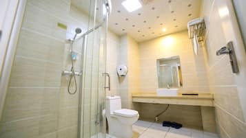 A bathroom with a glass shower enclosure, a toilet, and a sink with a mirror above it.