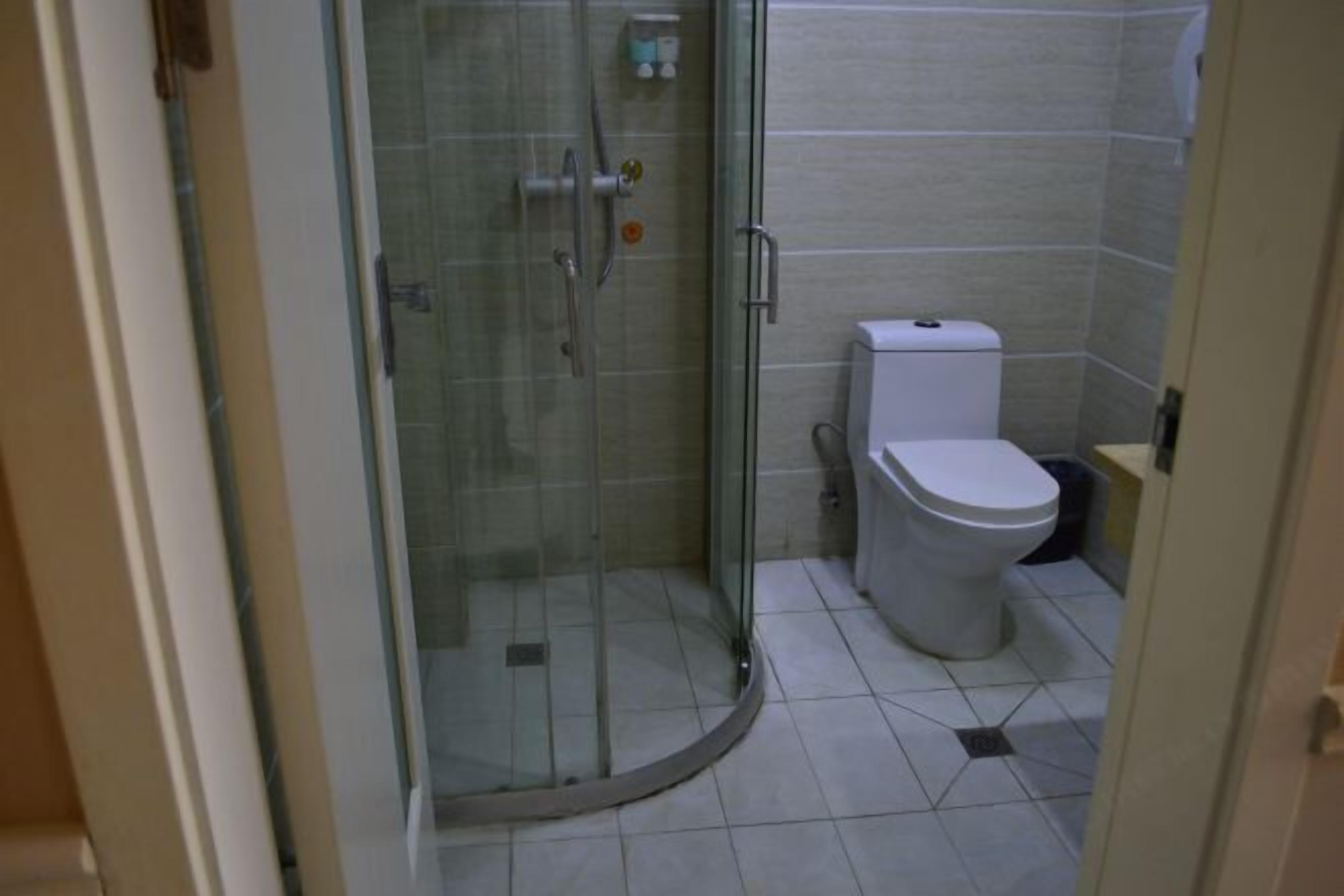 Ein Badezimmer mit Duschkabine, Toilette und Fliesenboden.