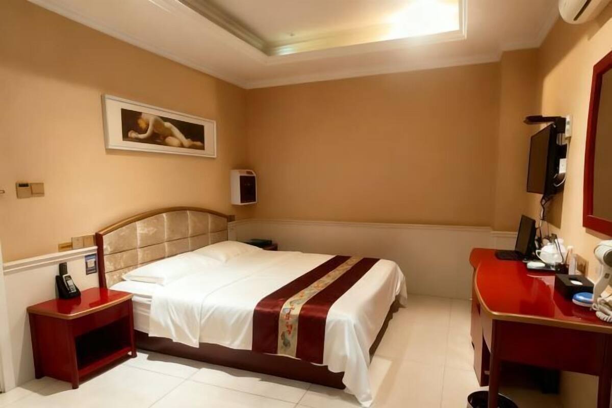 Une chambre d’hôtel équipée d’un lit, d’un bureau, d’une chaise, d’un téléphone et d’une télévision.
