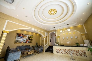 A hotel lobby with a reception desk, seating area, and a staircase. - Xingshan Luoma Holiday Hotel (Xingshan)