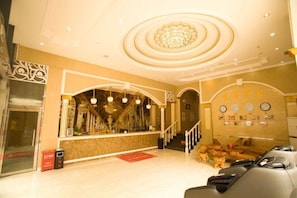 A hotel lobby with a reception desk, a staircase, and a seating area. - Xingshan Luoma Holiday Hotel (Xingshan)