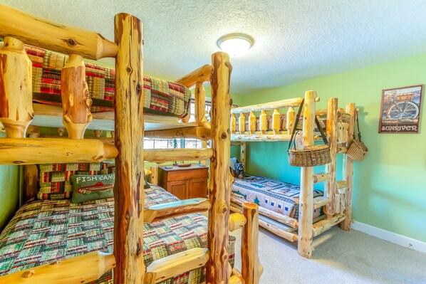Una habitación tipo cabaña con literas, muebles de madera y una pared verde.