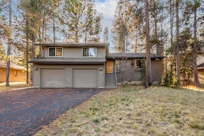 A two-story house with a garage, surrounded by trees. - BLUE08 - Family-Friendly Sunriver Retreat | Hot Tub + Bikes (Sunriver)