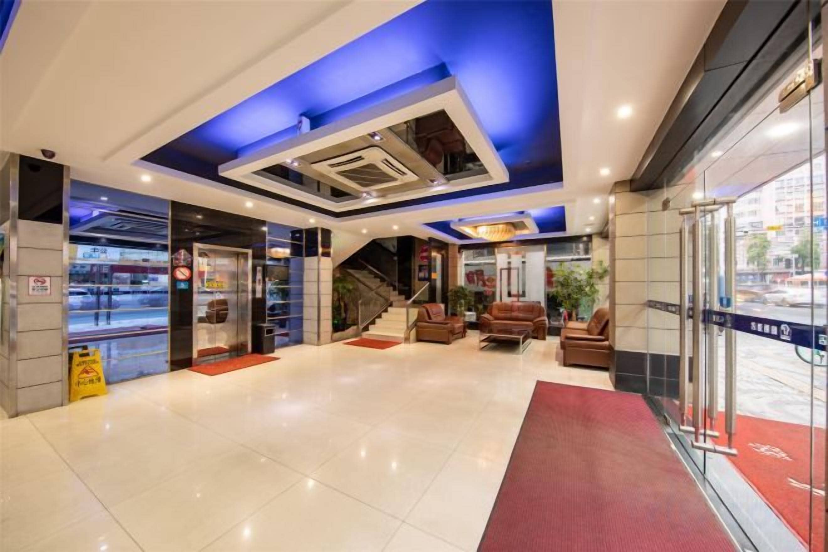 A hotel lobby with a staircase, seating area, and a glass entrance.
