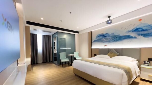 A modern hotel room with a large bed, a desk, and a chair. There is a painting on the wall and a TV on the left side. - Jiangmen ParkLane Hotel (Xiangshan Park Xinqiao Branch) (Jiangmen)