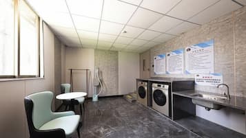 A public restroom with a washing machine, a sink, and a chair.