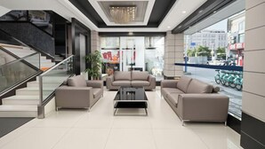 A modern lobby with a staircase, sofas, a coffee table, and a large window with a view of the street. - Jiangmen ParkLane Hotel (Xiangshan Park Xinqiao Branch) (Jiangmen)