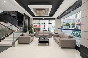 A modern lobby with a staircase, sofas, a coffee table, and a large window with a view of the street. - Jiangmen ParkLane Hotel (Xiangshan Park Xinqiao Branch) (Jiangmen)