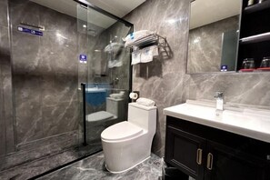 Une salle de bain moderne avec une douche à parois de verre, des toilettes blanches et un meuble-lavabo en bois foncé agrémenté d’un miroir.